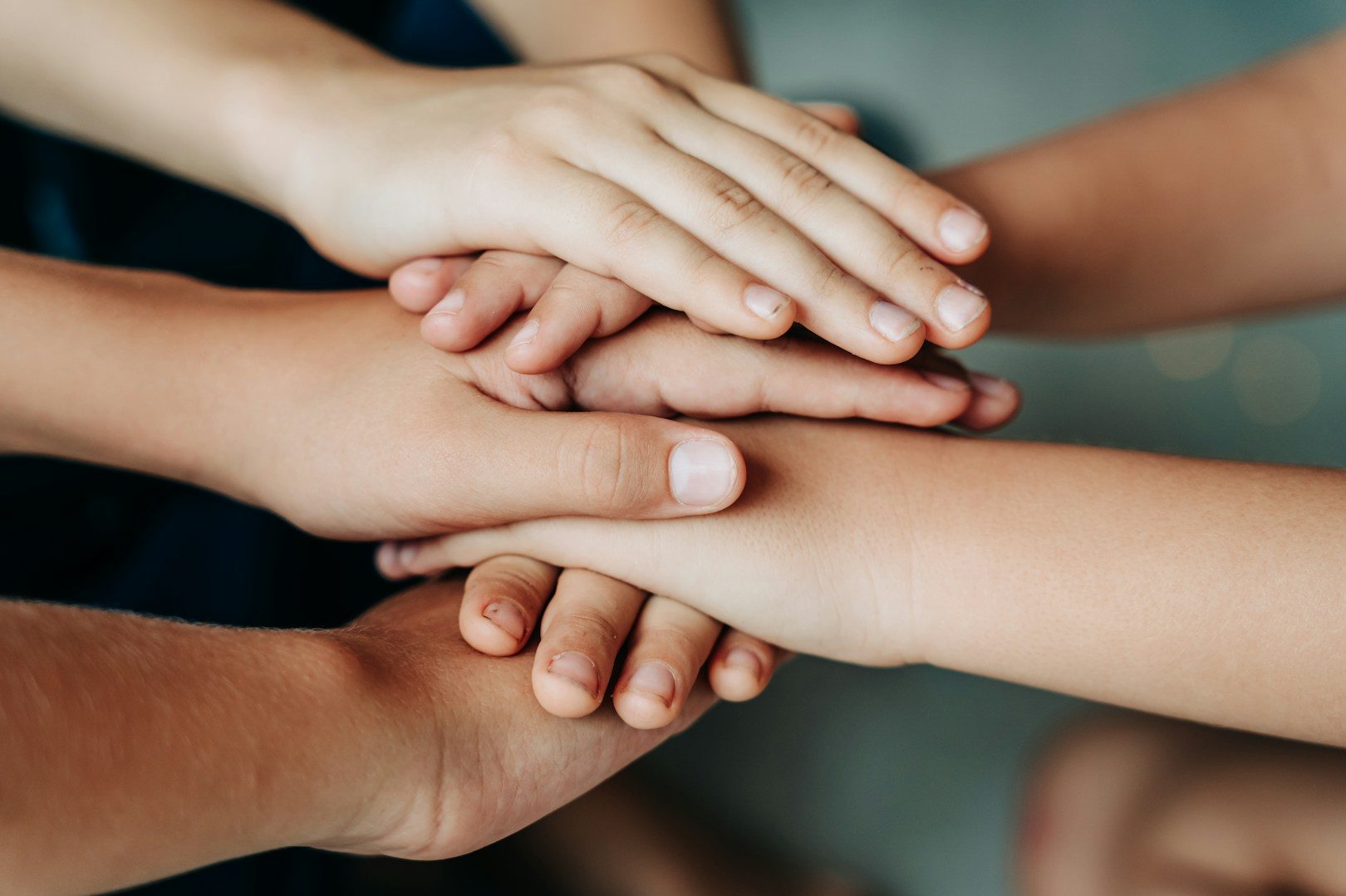 Hände übereinander als Symbol für Verbindung, Miteinander und bewusste Selbstführung im Familienalltag statt ständigem Organisieren.